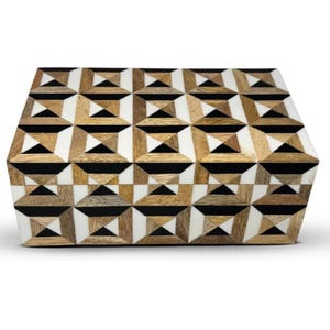 Puede incluir: Una caja rectangular de madera con un patrón geométrico de madera marrón claro, negro sólido y formas triangulares y cuadradas blancas. La tapa y el panel frontal muestran un diseño de mosaico repetitivo con líneas limpias y colores.