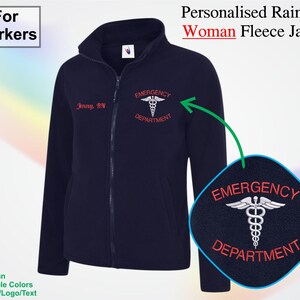 以下が含まれることがあります： ネイビーブルーのフリースジャケット。フルジッパー、"Emergency Department"と医療シンボルが刺繍されています。ジャケットには"Jenny, RN"という名前も付いています。左上には"For Workers"というテキストがあります。