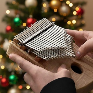 Peut inclure: Un kalimba en bois, instrument de musique à lamelles, est présenté devant un sapin de Noël. L'instrument possède des lamelles métalliques de différentes longueurs. Le corps en bois est rectangulaire avec un trou de résonance.