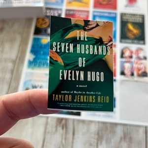 May include: A book cover with a green background and a woman lying on a bed. The title is "The Seven Husbands of Evelyn Hugo" by Taylor Jenkins Reid.