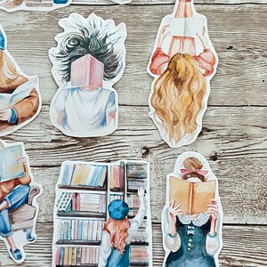 May include: A set of watercolor stickers featuring people reading books. The stickers are on a wooden background. The stickers are all different sizes and shapes. Some of the stickers feature people reading books with their faces covered by the book. Others feature people reading books with their faces visible. The stickers are all in a watercolor style and are very colorful.