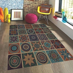 May include: A rectangular area rug with a geometric pattern of squares, each containing a different design. The designs include circles, stars, and floral motifs in shades of teal, brown, orange, and purple. The rug is on a wooden floor.
