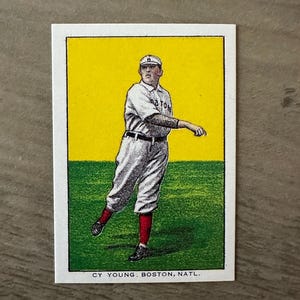 Può includere: Carta da baseball vintage con Cy Young dei Boston Nationals. La carta presenta un'illustrazione a colori di un giocatore di baseball in uniforme bianca con calzini rossi, su uno sfondo giallo e verde. Il testo "CY YOUNG. BOSTON, NATL." è stampato in basso.