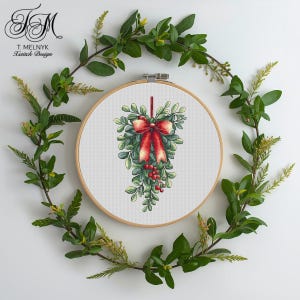 Könnte beinhalten: Ein Kreuzstich-Design eines Mistelzweigs mit roter Schleife und Beeren, in einem hölzernen Stickrahmen. Das Design ist von einem Kranz aus grünen Blättern umgeben. Der Text "T. Melnyk A Stitch Design" befindet sich oben links.