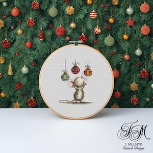 May include: A cross-stitch embroidery hoop with a cartoon mouse looking up at three Christmas baubles. The baubles are red, green, and gold. The background is a Christmas tree with various decorations. The hoop is made of wood.