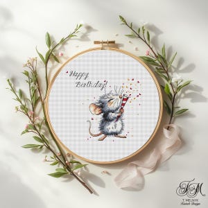 Puede incluir: Un bastidor de bordado de punto de cruz con un ratón de dibujos animados sosteniendo un petardo, con el texto "Happy Birthday!". El ratón es gris y blanco, con un petardo rojo y blanco. El bordado está rodeado de vegetación y flores.