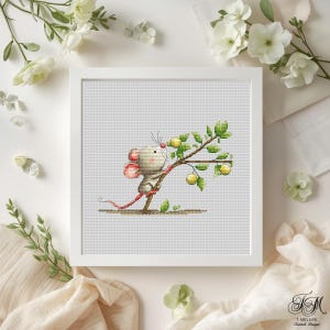May include: A framed cross-stitch artwork featuring a cartoon mouse with pink ears and a long pink tail, perched on a branch with green leaves and yellow fruit. The mouse is holding onto the branch. The artwork is in a white frame.