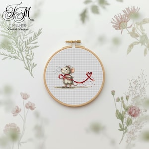 Puede incluir: Un bordado de punto de cruz en un aro de madera presenta un ratón encantador con una cinta roja. El ratón está sobre un fondo a cuadros. El texto "T. Melnyk A'stitch Design" está en la esquina superior izquierda.