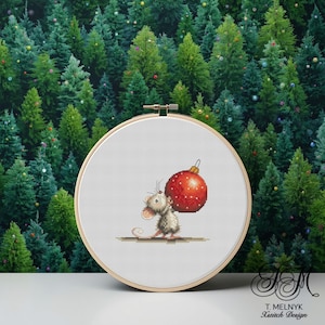 May include: A cross-stitch design of a mouse carrying a large red Christmas ornament. The ornament has white polka dots. The design is set in a wooden embroidery hoop. The background is a forest of green Christmas trees.