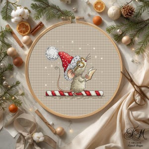 May include: A cross-stitch embroidery project in a wooden hoop featuring a mouse wearing a red and white polka-dot Santa hat and gold-rimmed glasses. The mouse stands on a red and white striped candy cane while holding a small open book.