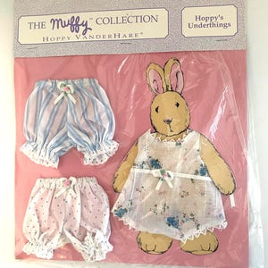 May include: A packaged "Muffy Collection" set featuring a bunny doll and two pairs of bloomers. The bunny wears a floral dress. One pair of bloomers is pink with white polka dots, and the other is blue and white striped.