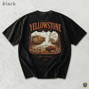 May include: Black t-shirt featuring a Yellowstone National Park graphic. The design includes a bison, geyser, and mountain landscape in shades of brown, orange, and white. The text "Yellowstone National Park" is arched across the top.