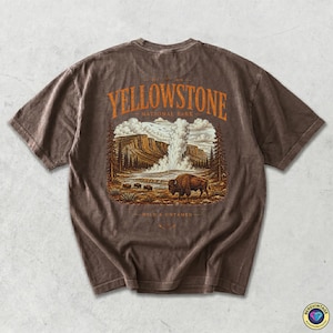 May include: Brown t-shirt featuring a Yellowstone National Park graphic. The design includes a bison, geyser, and text that reads "Yellowstone National Park" and "Wild & Untamed". The shirt has a vintage, worn look.