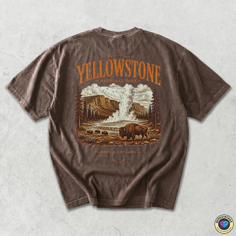 May include: Brown t-shirt featuring a Yellowstone National Park graphic. The design includes a bison, geyser, and text that reads "Yellowstone National Park" and "Wild & Untamed". The shirt has a vintage, worn look.