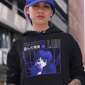May include: Black hoodie featuring a graphic of an anime character with the text "SERIAL EXPERIMENTS LAIN" in English and Japanese. The design is in shades of blue and purple. The hoodie has a drawstring hood and a front pocket.