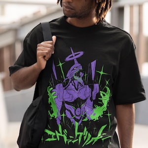 May include: Black t-shirt featuring a graphic design of a purple and green anime character with Japanese text. The design includes a halo and starbursts. The shirt is short-sleeved.