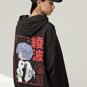 May include: Black hoodie featuring a Japanese anime character illustration in red and white. The design includes Japanese text and a stylized image of a character with blue hair. The hoodie has a drawstring hood and a relaxed fit.