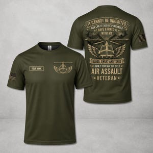 Op de afbeelding: Een olijfgroen t-shirt met een afbeelding op de voorzijde van een helikopterembleem en een vakje met de tekst YOUR NAME. De achterzijde toont een helikopter met vleugels en de tekst IT CANNOT BE INHERITED, BLOOD, SWEAT AND TEARS, AIR ASSAULT VETERAN.