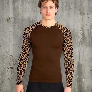 May include: A long-sleeve compression shirt featuring a solid dark brown torso and sleeves patterned with a tan and black leopard print. The garment has a round neckline and raglan-style sleeves that extend from the collar to the cuffs.
