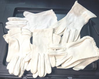 May include: A pile of white cotton gloves with delicate embroidery. The gloves are arranged in a casual manner, showcasing their soft texture and intricate details.