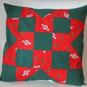 May include: A red and green patchwork pillow with a star design. The fabric features a white polka dot pattern, candy canes, and holly.