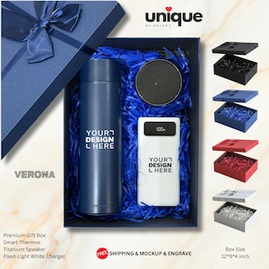 Può includere: Una scatola regalo blu navy contenente un thermos blu navy, un altoparlante nero rotondo e un power bank bianco con display digitale al 100%. Gli oggetti poggiano su carta blu sminuzzata. La scritta "YOUR DESIGN HERE" è presente sul thermos e caricatore.