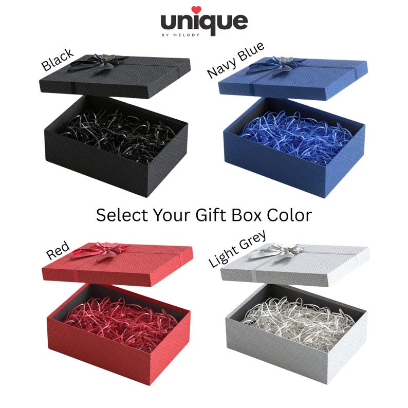 May include: Four rectangular gift boxes with lids, each featuring a textured surface, a decorative ribbon bow on top, and matching shredded paper filler inside. The boxes are available in black, navy blue, red, and light grey. Text reads: unique by melody, Select Your Gift Box Color, Black, Navy Blue, Red, Light Grey.