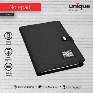 Può includere: Blocco note nero con chiusura bianca e la scritta "YOUR DESIGN HERE". Il blocco note ha una batteria integrata, un supporto per telefono e opzioni di incisione laser. La parola "Notepad" è in testo rosso in alto.