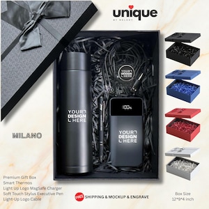 Può includere: Una confezione regalo nera contenente un thermos nero, un power bank nero con display digitale al 100%, una penna stilo nera e un cavo di ricarica. Il thermos e il power bank riportano il testo YOUR DESIGN HERE. La scatola ha un nastro nero.