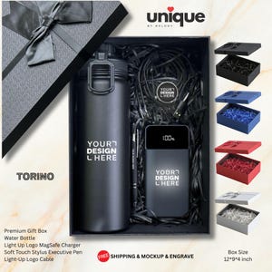 May include: A black gift box containing a matte black water bottle, a black power bank with a digital display showing 100%, a black stylus pen, and a black charging cable. The items are nestled in black shredded paper filler. The box lid features a black ribbon.