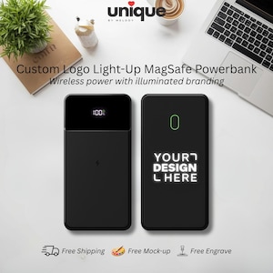May include: Two black rectangular MagSafe power banks. The left unit displays a digital 100% battery indicator and a lightning bolt icon. The right unit features an illuminated outline and the text YOUR DESIGN HERE in a glowing white font.