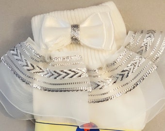 May include: White socks with a silver and white ruffle trim and a white bow with a silver center. The socks are labeled "piccolo" and "FIT 3-4 1/2".