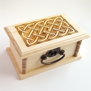 May include: A wooden box with a Celtic knot design carved into the lid. The box has a metal latch and handle.