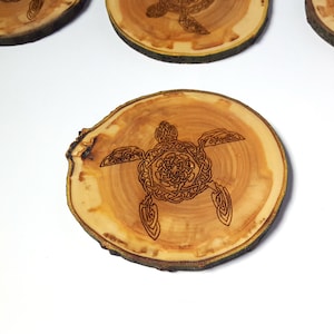 May include: A wooden coaster with a Celtic knot design of a sea turtle. The coaster is made from a natural wood slice with a rustic finish.