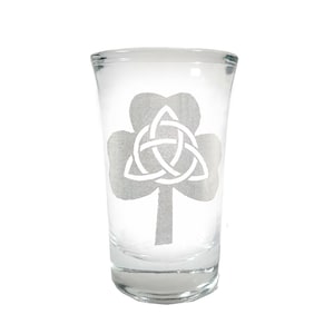 May include: A clear glass shot glass with an etched design of a shamrock with a Celtic knot in the center.