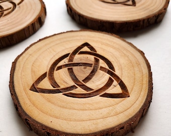 May include: Three wooden coasters with a Celtic knot design carved into the surface. The coasters are made from natural wood and have a rustic look.