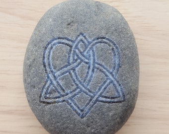 Puede incluir: Una piedra gris con un diseño de nudo celta tallado.