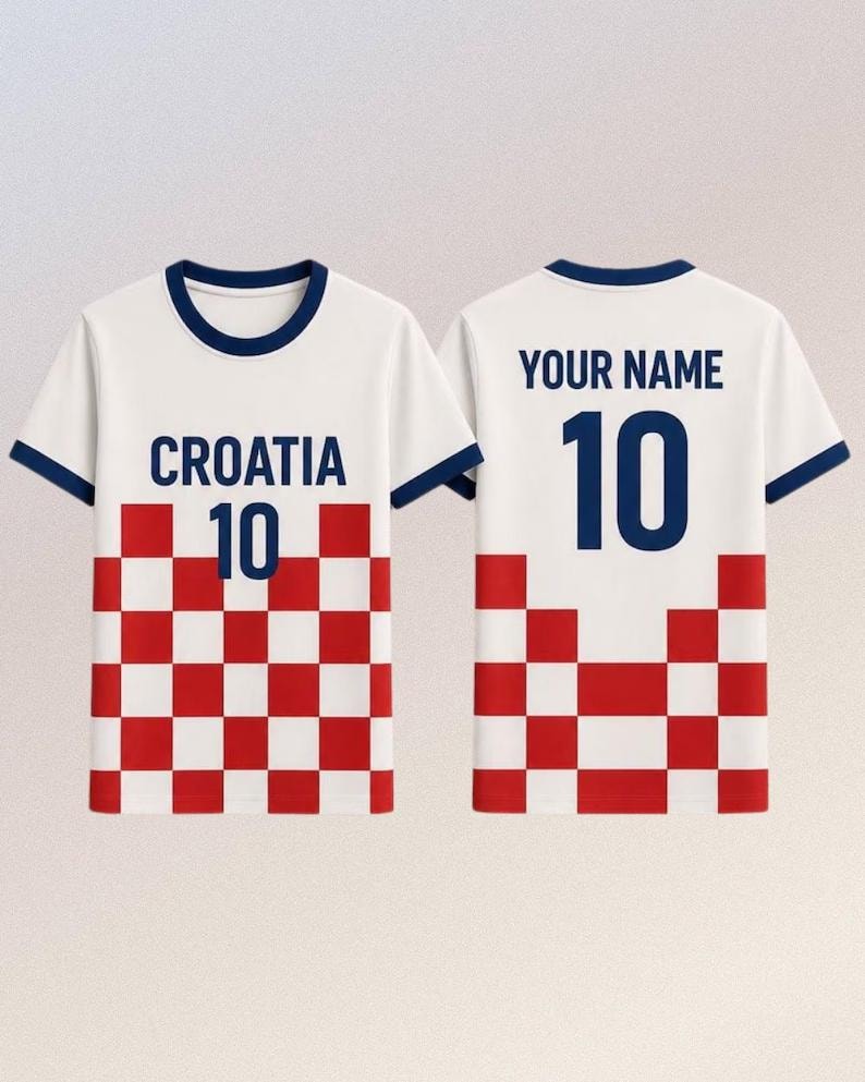 May include: A white short-sleeved t-shirt with dark blue trim on the collar and sleeves. The front features the text CROATIA above the number 10 and a red and white chequered pattern. The back displays the text YOUR NAME above the number 10.