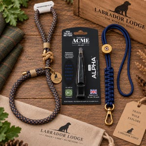 May include: A navy and tan rope slip lead with a brass tag, a black Acme Alpha 210.5 dog whistle on a display card, and a navy blue paracord lanyard with a brass clip and tag, all featuring Labrador Lodge branding.