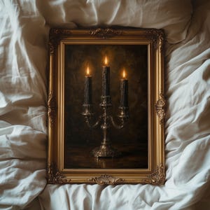 May include: A rectangular wall art piece featuring a metallic candelabra with three lit black candles, encased in an ornate gold frame. The painting depicts a dark, textured background with the warm glow of flames illuminating the candle wax.