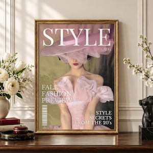 Può includere: Una stampa artistica incorniciata che raffigura una copertina di rivista intitolata STYLE AUG. L'immagine mostra una persona che indossa un grande cappello rosa con tessuto velato sul viso e un abito rosa con volant. Il testo recita FALL FASHION PREVIEW e STYLE SECRETS FROM THE 20's.