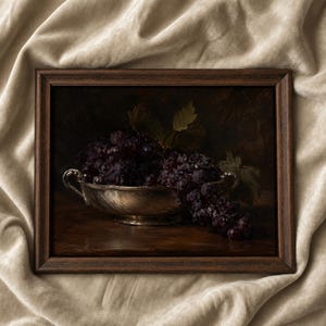 May include: A framed oil painting depicting a dark, moody still life of a cluster of deep purple grapes resting in a polished silver bowl with two handles. The grapes spill over the edge of the metallic vessel, set against a dark, shadowed background.