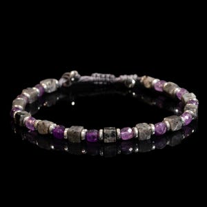 May include: A beaded bracelet featuring alternating square-cut grey stone beads and faceted purple gemstone beads, separated by small silver-toned metal spacers. The bracelet includes an adjustable cord closure with two small silver-toned metal beads.
