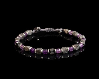 May include: A beaded bracelet featuring alternating square-cut grey stone beads and faceted purple gemstone beads, separated by small silver-toned metal spacers. The bracelet includes an adjustable cord closure with two small silver-toned metal beads.