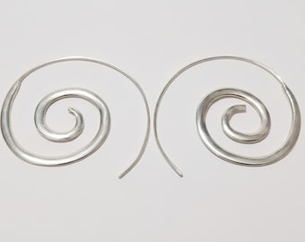 May include: A pair of silver spiral earrings. Each earring has a curved wire forming a spiral shape with a rounded centre. The earrings are shown against a plain white background.