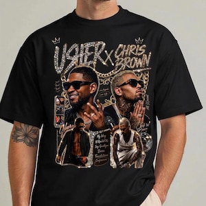 Pode incluir: Uma t-shirt preta com uma estampa gr&aacute;fica de Usher e Chris Brown. O design inclui detalhes de correntes douradas, texto estilo diamante escrito USHER X CHRIS BROWN e pequenas fotos dos artistas.