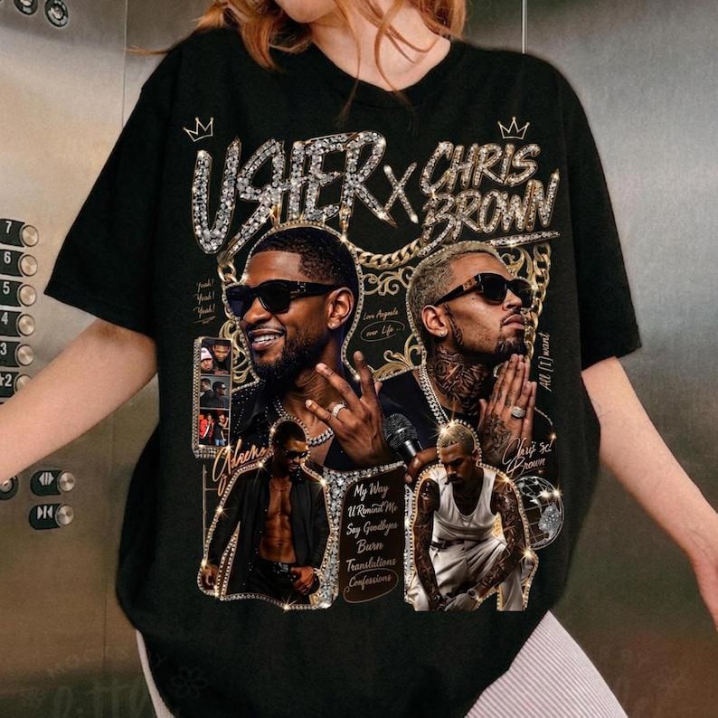 Pode incluir: Uma t-shirt preta com uma estampa gr&aacute;fica de Usher e Chris Brown. O design inclui detalhes de correntes douradas, coroas e o texto Usher x Chris Brown, My Way, U Remind Me, Say Goodbye, Burn, Translations e Confessions.