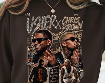 May include: A dark brown crewneck sweatshirt featuring a graphic print of Usher and Chris Brown wearing sunglasses. The design includes gold chain accents, crowns, and text reading Usher x Chris Brown, My Way, U Remind Me, Say Goodbye, Burn, and Confessions.