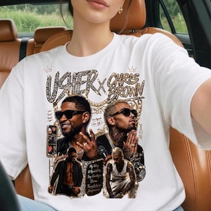 Pode incluir: Uma t-shirt branca de manga curta com uma impress&atilde;o gr&aacute;fica de Usher e Chris Brown. O design inclui texto em tom dourado, letras com padr&atilde;o de diamante e pequenas inser&ccedil;&otilde;es de fotos dos artistas. A impress&atilde;o cont&eacute;m t&iacute;tulos de m&uacute;sicas.
