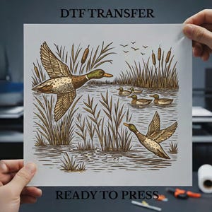 May include: A DTF transfer featuring a detailed illustration of ducks in a marsh setting. The design includes ducks in flight and swimming, with cattails and water depicted in brown and tan tones. The text "DTF TRANSFER" and "READY TO PRESS" are visible.